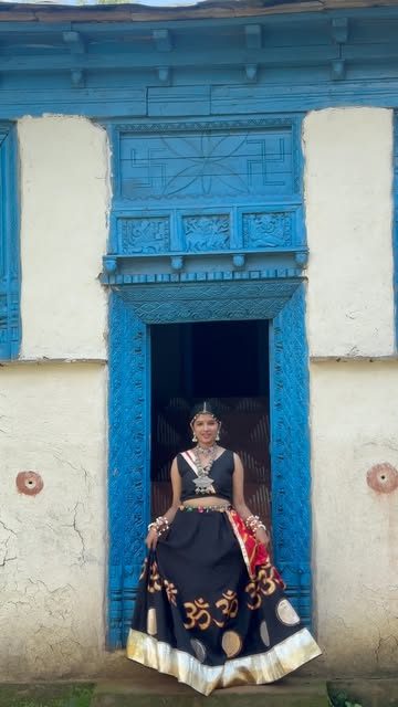 Black garba chaniya with gold Om motifs at a blue carved door